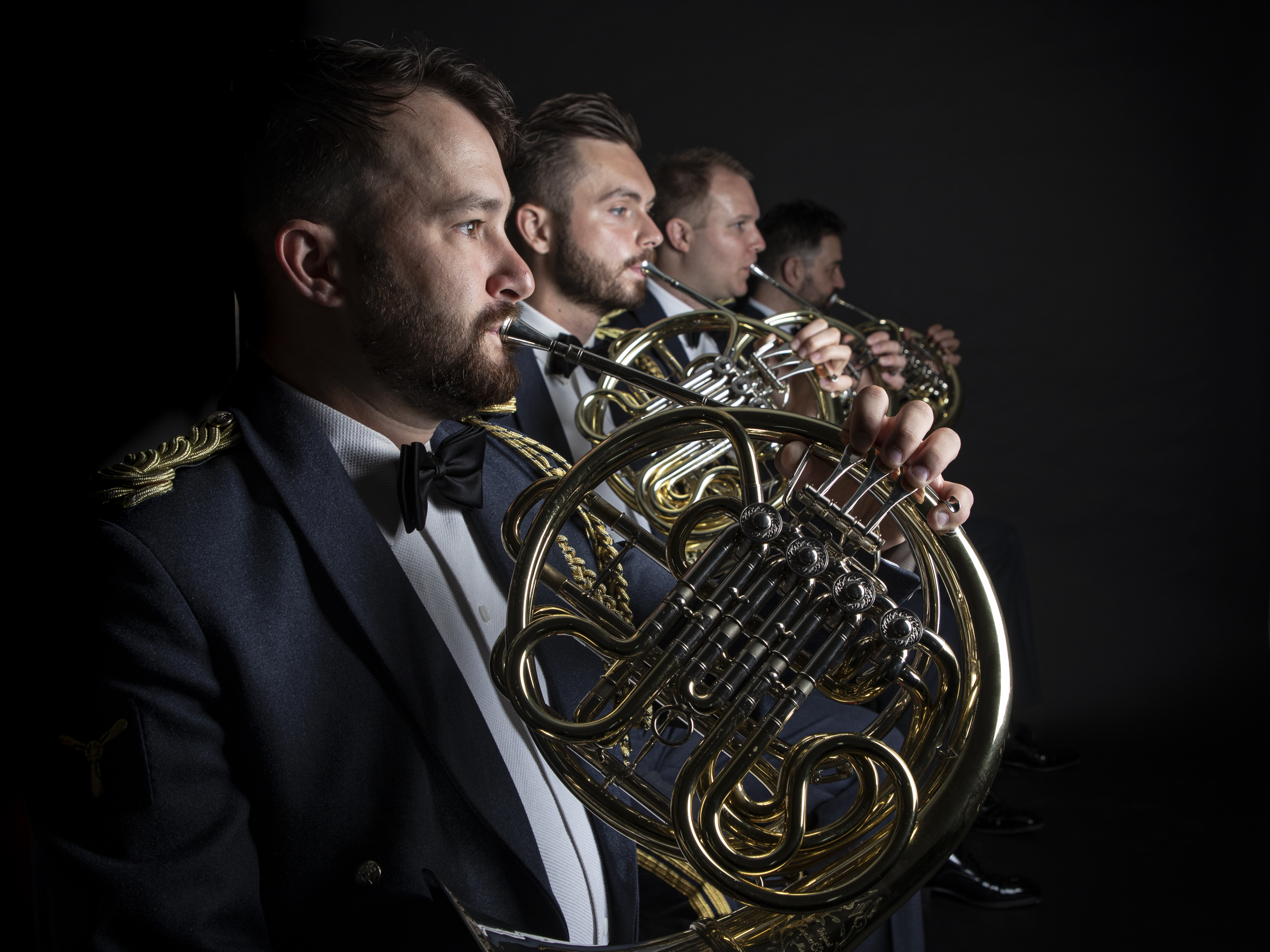 Side shot of four RAF Musicians playing brass instruments.